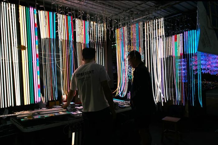 A market stall aglow with rope lights, featuring two people in the foreground.