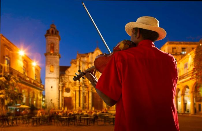 A violinist performing at night in Plaza de la Catedral, Havana, Cuba