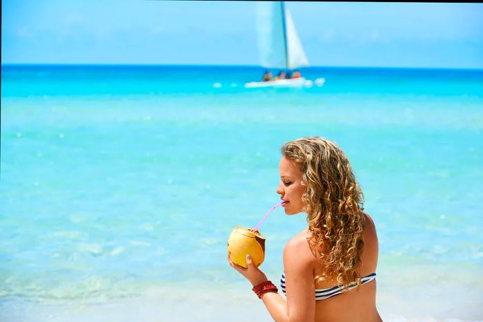 A woman enjoys a cocktail while relaxing on a Cuban beach