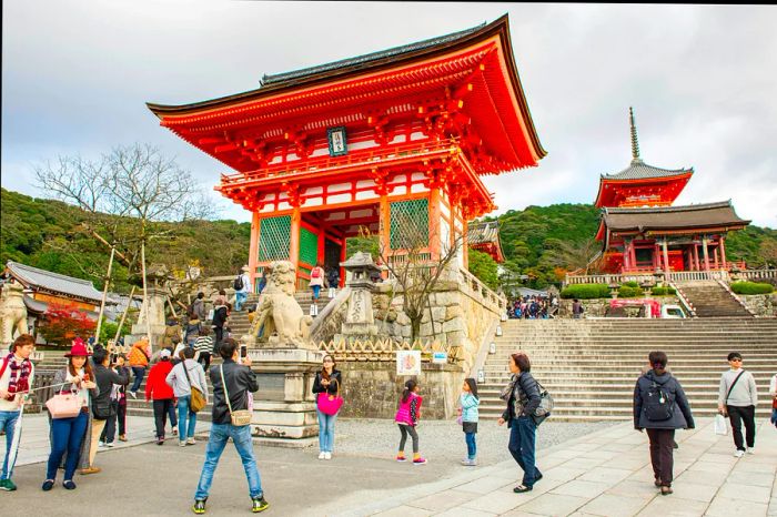 Autumn visitors enjoying the sights and capturing photos of Kiyomizu-dera in Kyoto, Japan.