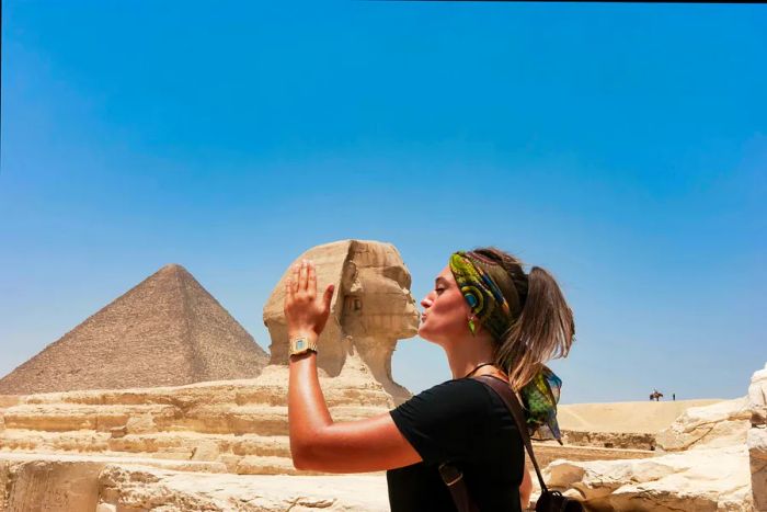 A woman poses to kiss the Sphinx using a perspective trick for a photograph