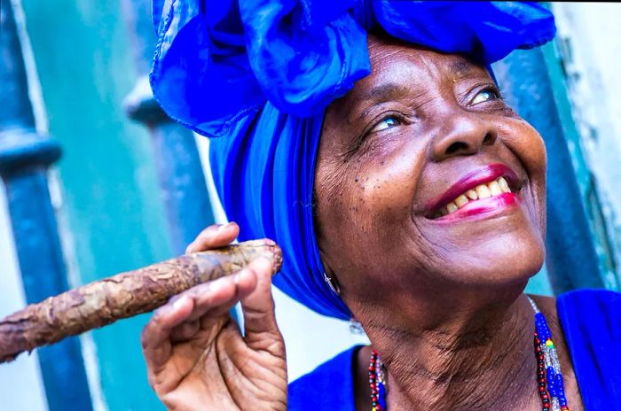 Portrait of an Afro-Cuban woman enjoying a cigar and smiling in Havana, Cuba.