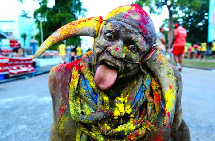 A carnival reveler, face painted and sporting horns, poses for a portrait during the J'ouvert street procession as part of Trinidad Carnival.