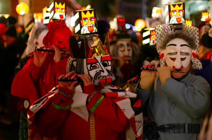 Close-up of piccolo players in costumes adorned with illuminated head lanterns at Fasnacht in Basel, Switzerland.