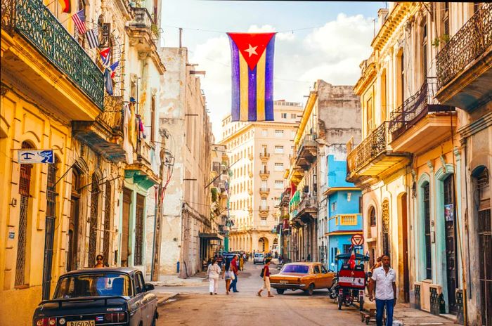 The Cuban flag, adorned in red, white, and blue, gracefully hangs between buildings in a street in Old Havana.