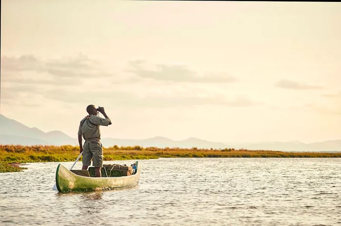 A wildlife guide steers a canoe along the Zambezi River in Mana Pools National Park, Zimbabwe.