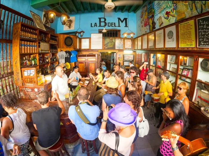 A lively crowd gathers around a bar as musicians entertain