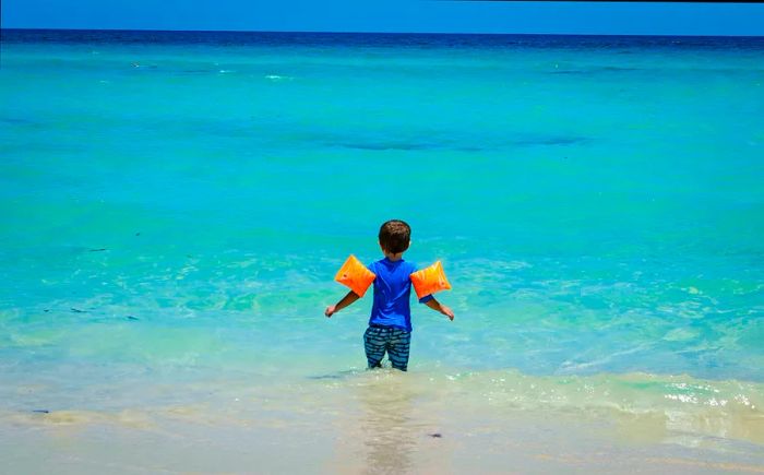 A young child in floaties enjoying a Cuban beach