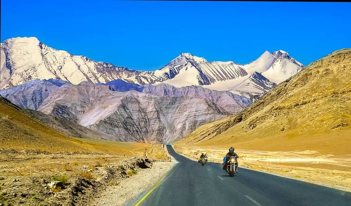 Motorcyclists navigating a highway with mountains in the background, Ladakh, India