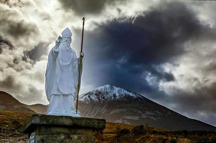 A statue of St. Patrick stands proudly in front of Croagh Patrick, known as the Reek, a 764-meter mountain and a significant pilgrimage site in County Mayo, Ireland.