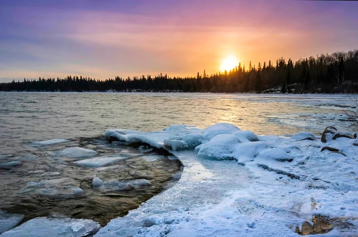 A stunning sunset over Cold Lake Provincial Park in Alberta, featuring a snow-covered shoreline.