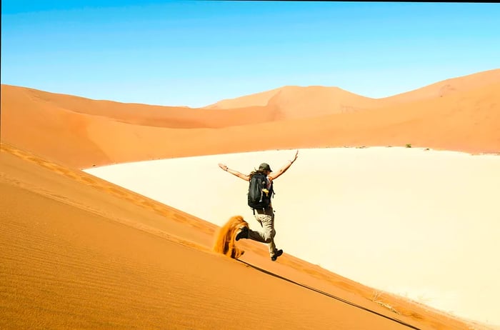 A woman races down a sand dune near Deadvlei, Namib Desert, Namibia