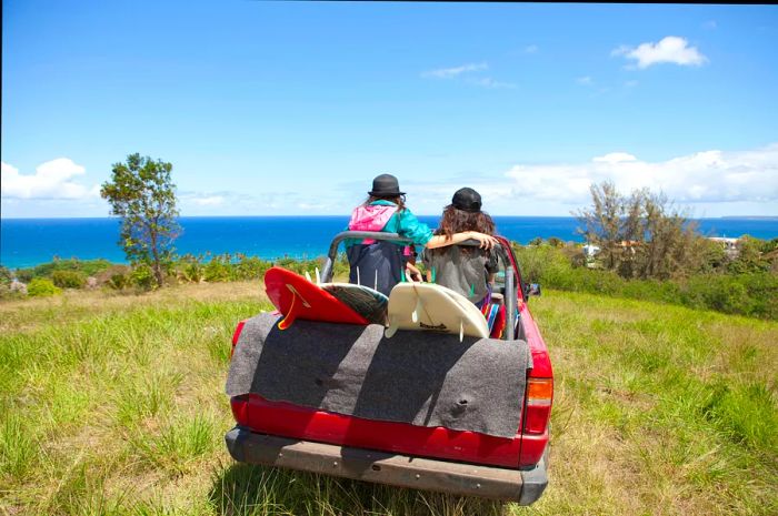 An off-road vehicle makes its way toward a beach with two women riding in the back.