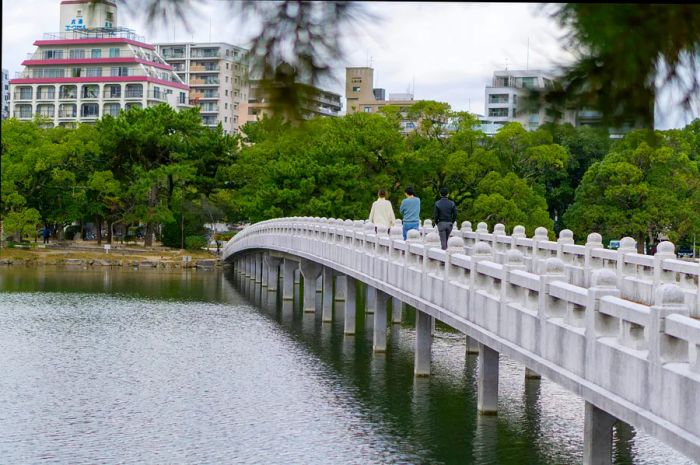 People stroll across Kangetsu Bridge in Ōhori Park, Fukuoka, Japan