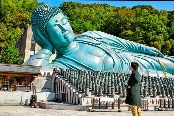 A grand bronze reclining Buddha statue in a park setting