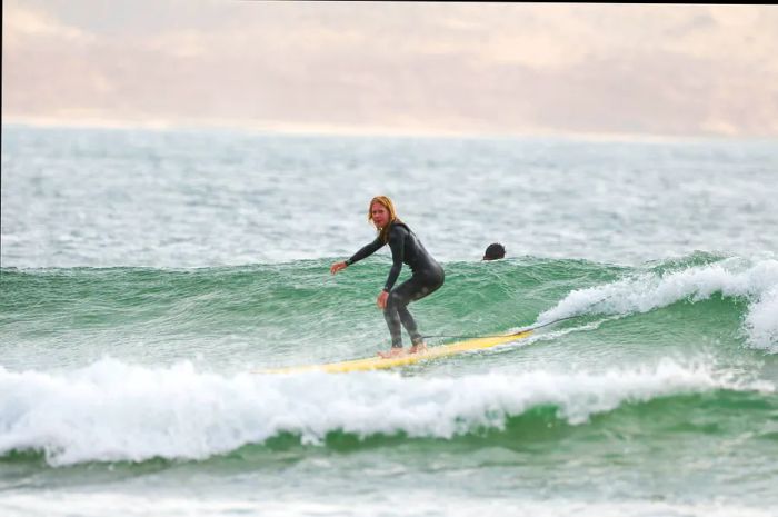 Sally Kirby catches a wave on her longboard in Imsouane, Morocco