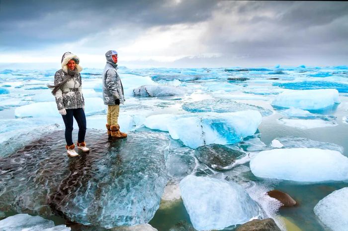 Tourists stand atop the massive icebergs at Jökulsárlón lake in Iceland during winter.