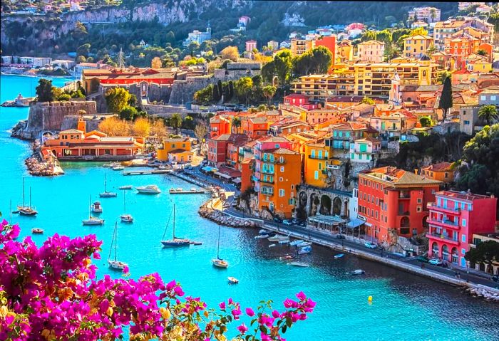 A picturesque view of the village of Villefranche-sur-Mer, adorned with yachts and vibrant purple bougainvillea, located in Côte d’Azur, France