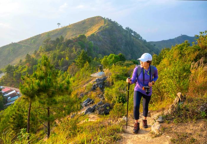 A young Asian woman hiking on a mountain with a steep cliff in Thailand