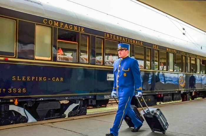 A wagon conductor assists passengers by transporting their luggage for hotel transfers on the Orient Express.