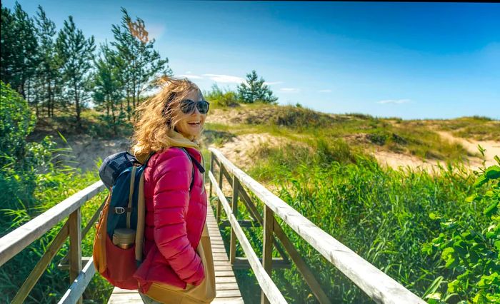 A young, joyful girl strolls along the chilly shores of the Baltic Sea on a windy, sunny day.