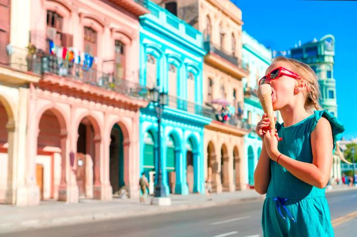 A child enjoys an ice cream on the street in front of colorful pastel buildings