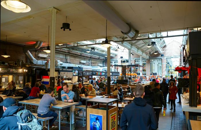 The bustling interior of Foodhallen in Amsterdam, where diners share tables and enjoy various cuisines.