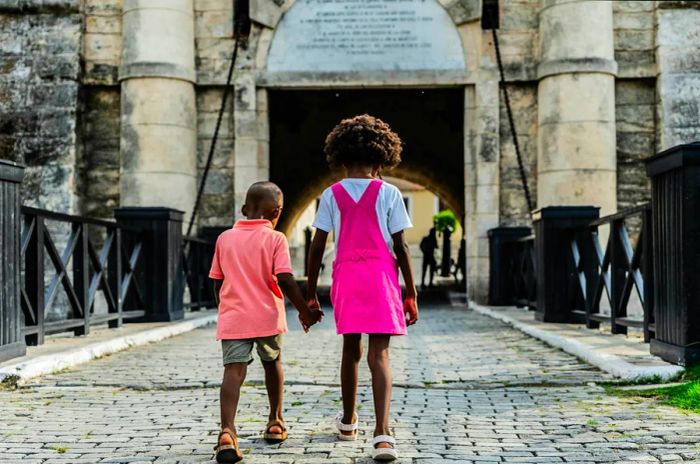 Siblings walk across a bridge leading to a historic fort