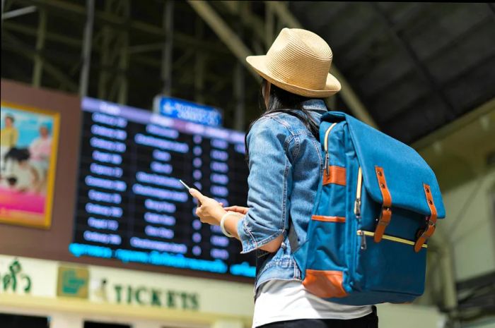 A young woman reviews the travel timetable board