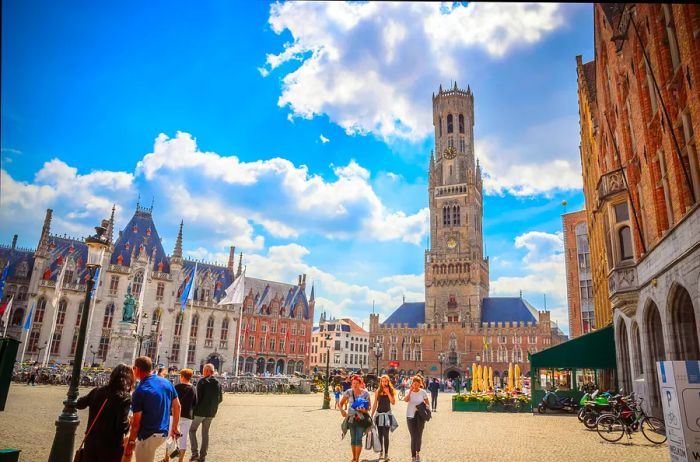 Visitors stroll through a vast medieval square dominated by a towering Gothic structure.