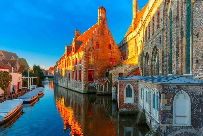 The exterior of the Museum Sint-Janshospitaal reflected in the canal on a calm winter morning with a clear blue sky in Bruges, Belgium