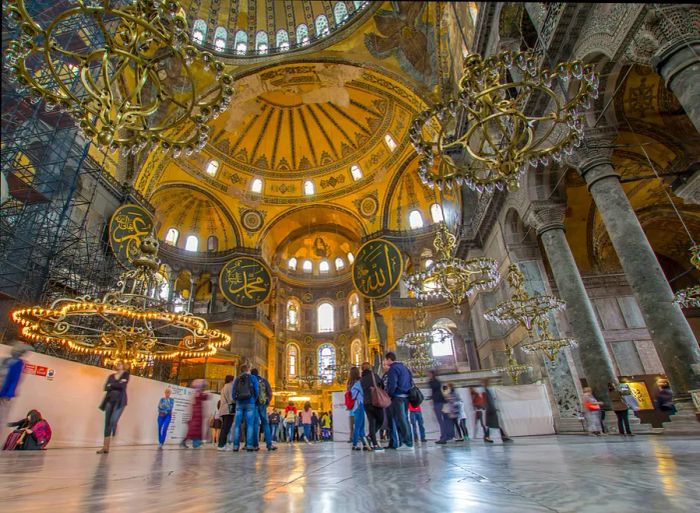 A captivating interior view of a grand mosque featuring a magnificent central dome and stunning chandeliers cascading from the ceiling.