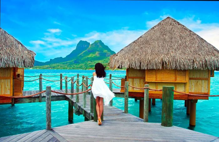 A woman gazes from her overwater bungalow towards the mountains of Bora Bora.