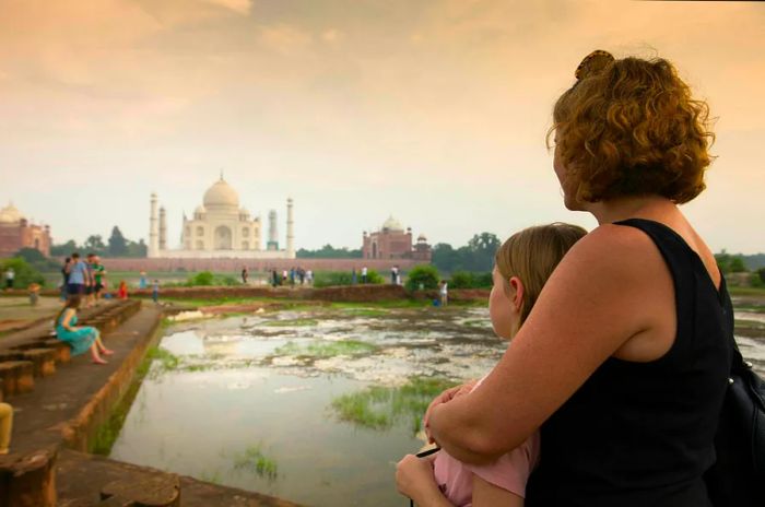 A mother and daughter admiring the Taj Mahal at sunset