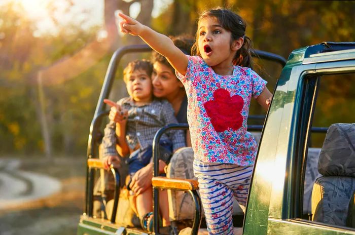 A mother and her two children enjoying an exciting safari in an off-road vehicle in India.