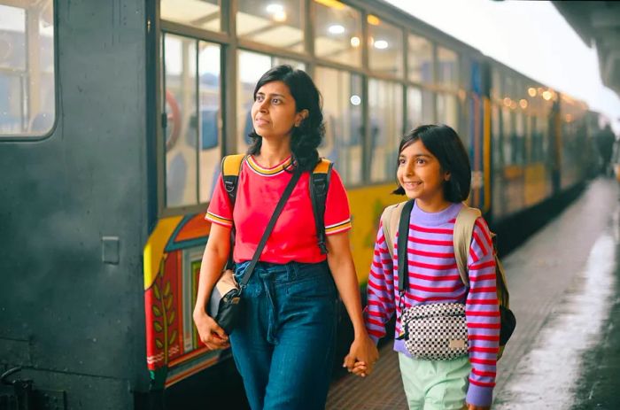 A mother and daughter stroll along a train station platform in India.