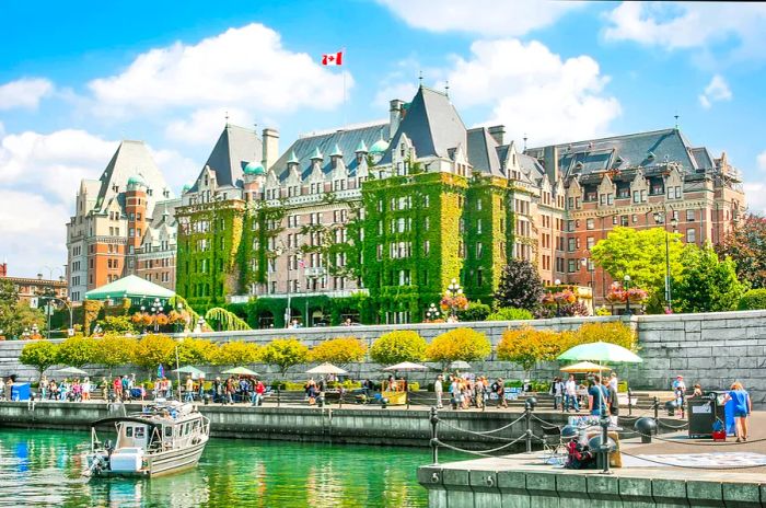 A Canadian flag waves proudly above a large, ivy-covered building by the waterfront.