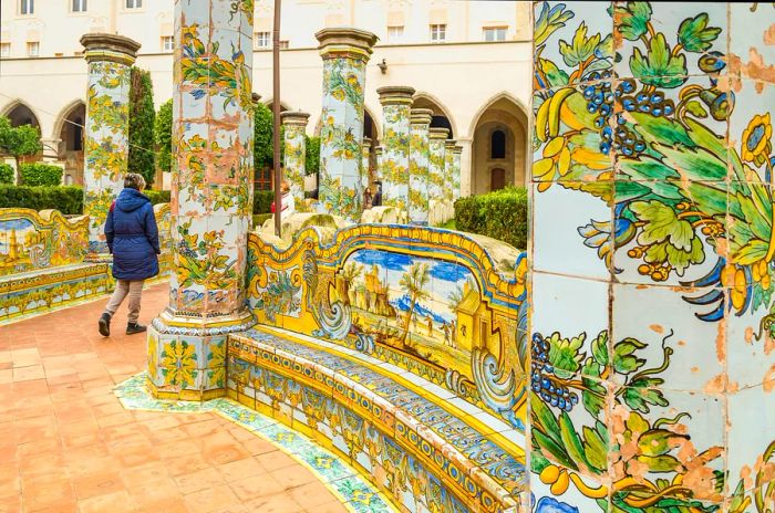 A woman strolls past a vibrantly painted bench at Santa Chiara.