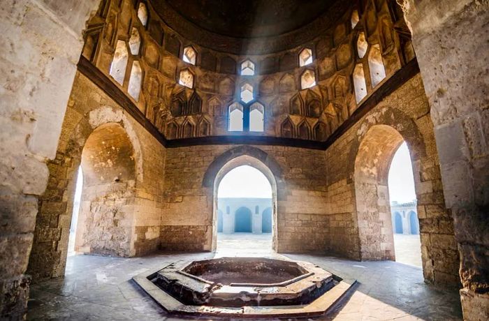 Light streams through windows into a hexagonal structure within a mosque complex