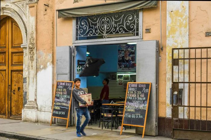 A young boy strolls past a quaint “menú” restaurant in Lima's Historic Center, a favorite spot for those seeking a set-lunch meal.