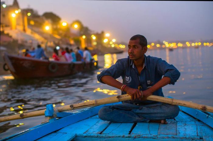 A close-up of a boatman holding oars on the Ganga River at night, Varanasi, India