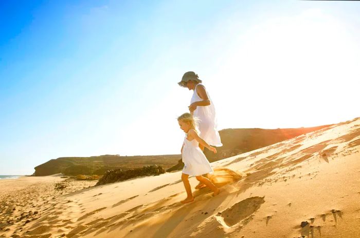 Spain, Fuerteventura, mother and daughter running together on the beach