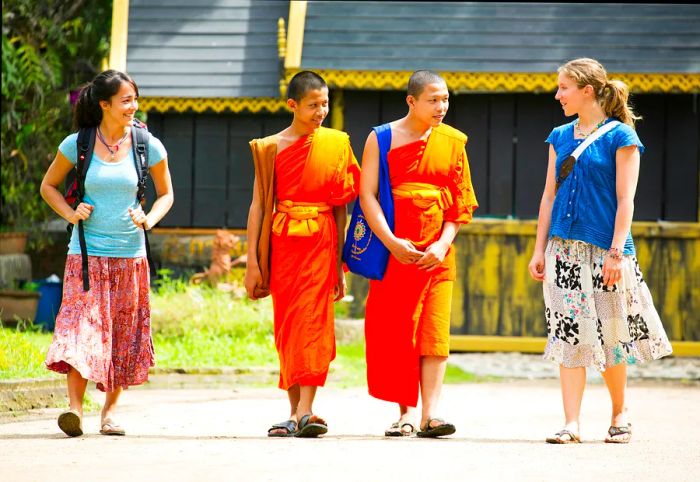 Two female travelers engaging in conversation with local monks in Chiang Mai, Thailand