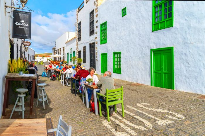 Tourists enjoying a meal at a local restaurant in the historic town of Teguise, which once served as the capital of Lanzarote and is now a popular attraction.