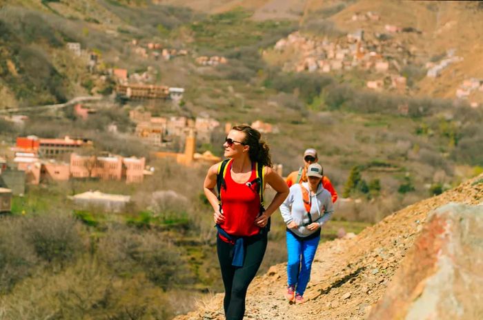 Three hikers ascend a path in a rugged mountain landscape