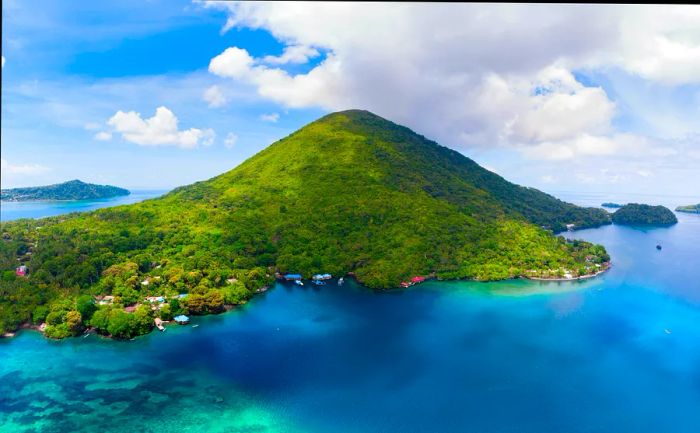 Aerial view of Pulau Gunung Api featuring small buildings scattered along the island's outskirts.