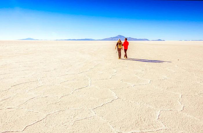 Tourists strolling across the vast, white salt flats of Salar de Uyuni.