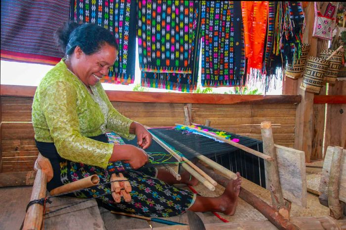 A woman skillfully weaving traditional handmade fabric on Flores Island.