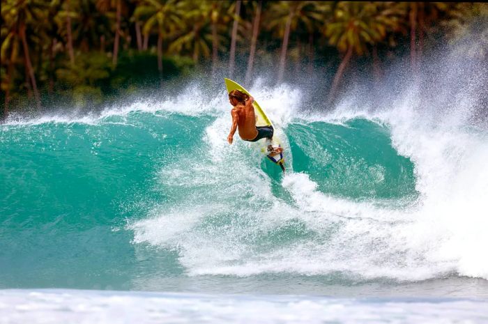 A surfer rides the waves at Lagundri Bay in North Sumatra, Indonesia.