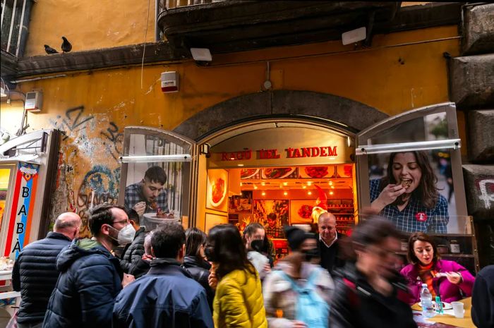 A crowd gathers outside a restaurant doorway, eagerly waiting for a table.